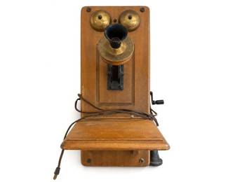 Antique Wooden Wall-Mounted Crank Telephone with Brass Bells
Condition: Good
Wooden wall-mounted crank telephone with twin brass bells at top, central mouthpiece/receiver opening, hinged shelf, and hanging cord. Decorative/collector-grade antique telephone rather than a modern working phone.