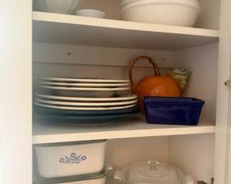 CorningWare Blue Cornflower casserole and bakeware lot
Condition: Good
Mixed lot of vintage white ceramic casserole/bakeware pieces with blue cornflower/floral decoration, including stacked lidded and unlidded dishes. Secondary items visible in the cabinet include dinner plates, bowls, and an orange decorative object, but the salable focus is the CorningWare-style bakeware group.