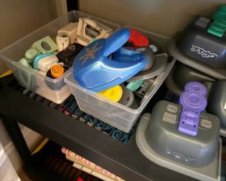 Assorted Paper Punch Lot
Condition: Good
Assorted scrapbooking/craft paper punches, mostly plastic-bodied punches in mixed colors and shapes, grouped together in small storage bins on a shelf. The lot appears to include multiple hole/shape punches; exact count, brand, and pattern mix are not confirmed from the photo.