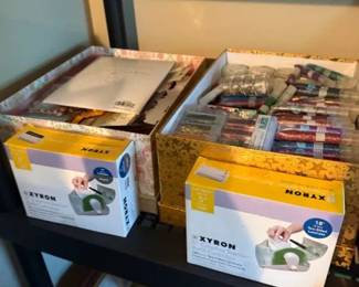 Xyron Creative Station sticker maker machine lot
Condition: Good
Two Xyron Creative Station sticker-maker boxes on a shelf, with multiple refill cartridges and craft consumables bundled nearby in decorative storage boxes. Condition appears good with box wear typical of stored inventory; exact model, cartridge types, and completeness are not fully readable from the image.