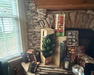 Christmas holiday mantel decor mixed lot with lantern-style accents, glass ornaments, candles, and boxed greenery
Condition: Good
Assorted Christmas mantel decorations on and around a stone fireplace: at least one tall clear cylinder filled with red/gold ornaments, multiple boxed faux greenery items, a lantern-style piece, candles, and additional small holiday decor. The grouping appears to be a display lot rather than a single original set.