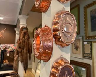 Copper-toned decorative Jell-O molds / wall-hanging cake molds, lot of 5
Condition: Good
Five copper-toned hanging molds with embossed floral/starburst and fluted designs, displayed as wall decor on a pillar. Likely vintage baking/Jell-O molds or similar decorative molds. Secondary objects in the room are not part of the sale item.
