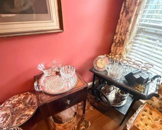 Vintage clear glass punch bowl serving set with cups and tray
Condition: Good
Clear glass entertaining set displayed on small tables near a window. Visible components include multiple matching handled cups, a large decorative clear bowl or serving vessel, and additional glass pieces that may belong to the same punch set. Several silver-tone or reflective serving pieces are also present nearby, but the primary salable object is the punch-bowl-style glass service grouping.
