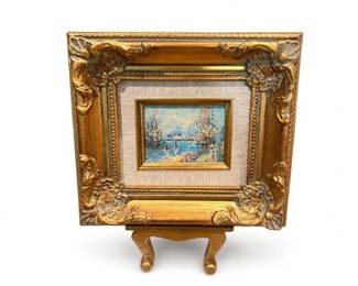 Ornate gilt-framed miniature landscape painting on easel
Condition: Good
Small framed miniature landscape scene with water, trees, and sailboats in an ornate gold frame with floral/scroll corner ornament; mounted on a small easel. Likely decorative hand-painted or print-based miniature art, but medium and authorship are unverified from the image alone.