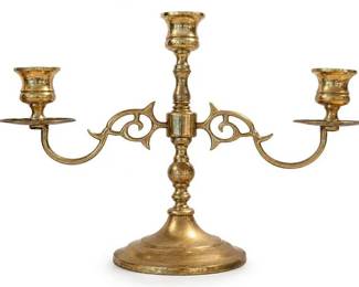 Brass three-arm candelabra candle holder
Condition: Good
Decorative brass tabletop candelabra with one central candle socket and two outward scrolling arms supporting two additional sockets. Ornate pierced scrollwork on the arms, turned column, and wide circular base. Surface shows aged patina/tarnish consistent with used brass.