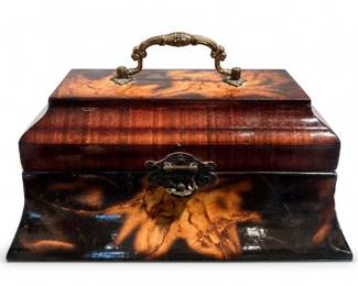Tortoiseshell-Style Veneered Jewelry Box with Brass Handle
Condition: Good
Small rectangular decorative box with a domed/sculpted profile, dark brown and amber mottled surface, brass swing handle, and ornate brass front clasp. Likely used as a jewelry, sewing, or keepsake box. Visible wear includes surface scuffs and finish wear, but no major breakage is apparent in the image.