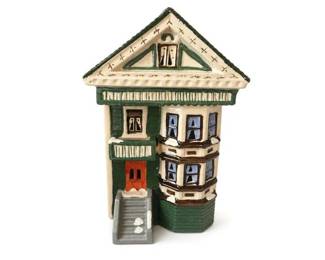 Hand-Painted Ceramic Miniature Village House Figurine
Condition: Good
Small decorative ceramic house with a steep gabled roof, green trim, cream body, bay window on the right side, orange front door, and molded front steps. Hand-painted look; likely intended as a village display piece or shelf decor. Condition appears visually good from the front, with no obvious major chips visible in this image, though underside and back were not shown.