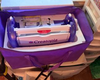 Creatopia Die Cutting and Embossing Machine
Condition: Good
Purple-and-white manual craft die-cutting/embossing machine in a purple tote bag, with visible Creatopia branding and some included accessories. Intended for paper crafting and scrapbooking.