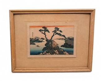 Framed Japanese woodblock landscape print
Condition: Good
Framed Japanese landscape woodblock print showing a rocky pine-covered island or shoreline scene with water and distant mountains. Condition appears generally good from the front, with age toning and wear to the frame/mat area visible.