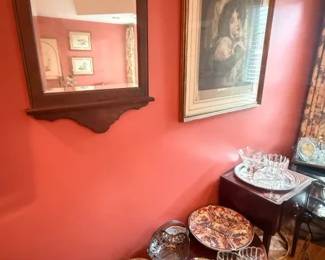 Ornate dark wood wall mirror
Condition: Good
Rectangular decorative wall mirror with dark carved wooden frame, arched/top crest shape, and shaped lower skirt. Visible in a coral-painted room; appears to be hanging in place and shows normal age-related finish wear rather than obvious breakage.