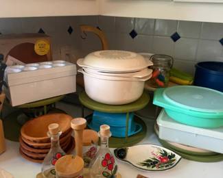 Cream Covered Casserole Dish
Condition: Good
Primary item appears to be a round cream/ivory covered casserole or serving dish with lid and side handles. The photo also shows other assorted kitchenware in the background, including pastel containers, a wooden tray with berry-printed glassware, and stacked bowls/dishes.