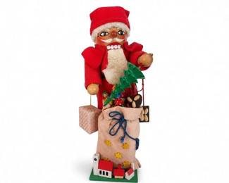 Handmade-style Santa Claus Christmas figurine with burlap sack and toys
Condition: Good
Standing Santa figure in a red hat and coat with cream faux-fur trim, painted face, wooden-looking hands, and a tan burlap-style sack decorated with stars and a blue cord. The figure appears to include several small toy/gift accents attached around the sack and base. Overall presentation reads as a decorative Christmas display piece rather than a functional toy.