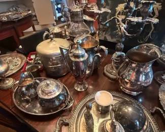 Ornate silver-plated tea and coffee service set with tray
Condition: Good
Large mixed silver-plated tea/coffee service grouping with ornate handles, lids, and presentation trays. Visible pieces include at least one tall coffee/tea pot, a lidded sugar bowl, creamers, and additional matching/near-matching serving vessels arranged as a display collection.