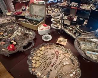 Mixed Costume Jewelry Lot with Rhinestone and Gold-Tone Pieces
Condition: Good
Large assortment of costume jewelry spread across multiple trays and boxes, including necklaces, bracelets, brooches/pins, earrings, and possibly rings. Visible finishes include gold-tone and silver-tone metal, faux pearls, and rhinestone or crystal-style accents. Secondary display items and jewelry boxes are present but should not be treated as part of the salable lot unless inventoried separately.