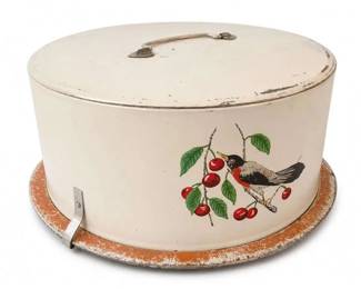 Maid of Honor Birds Berries Vintage Metal Cake Carrier
Condition: Good
Round vintage metal cake carrier with white enamel/tin body, domed lid, top carry handle, and side latch/clip. Exterior has a bird perched among red cherries with green leaves. Finish shows noticeable edge wear and age-related scuffing, especially on the base ring and lid rim.