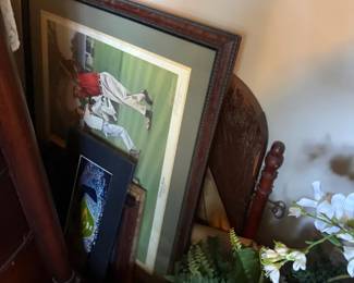 Framed equestrian art print in dark wood frame with green mat
Condition: Good
Single framed equestrian image in a dark wood frame with green matting. The visible artwork appears to depict a rider on horseback and is stored among other framed pieces; condition from the front appears generally good, though the photo does not show the back, glazing, or any label.