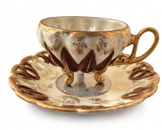 Vintage footed porcelain demitasse cup and saucer with gold and brown enamel decoration
Condition: Good
Footed porcelain demitasse cup with matching saucer, heavily gilded with brown raised enamel/scroll and chevron-style decoration. Handle is looped and the cup sits on small decorative feet. No obvious chips or cracks are visible in the photo, though underside marks are not shown.
