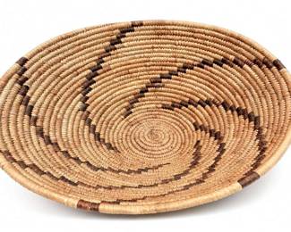 Handwoven Coiled Natural-Fiber Basket Tray
Condition: Good
Round shallow coiled basket or tray with concentric spiral construction, tan natural-fiber body, and irregular dark brown banding around the rim and face. Visible condition appears good from the single image, with no obvious breaks or missing sections.