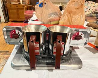 Campbell's Soup vintage countertop dual-cup soup warmer
Condition: Good
Vintage dual-well countertop soup warmer with chrome-toned body, two removable metal cups, brown vertical handles, and red front dials. Appears to be a commercial or promotional Campbell’s Soup serving/display piece.