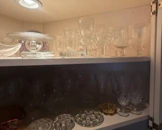 Clear Glass Assorted Stemware and Decorative Tableware Lot
Condition: Good
Assorted clear glass display and serving pieces in one cabinet: multiple stemmed glasses on the top shelf, several small footed bowls/compotes and crystal-like dishes on the middle shelf, and additional glassware below. Best sold as a mixed lot unless individually identified and measured.