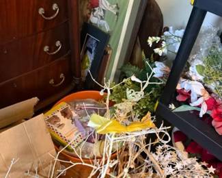 artificial floral arrangement in wicker basket
Condition: Fair
A generic artificial floral arrangement with mixed faux stems and white/yellow accents in a basket or low container. Condition appears used/dusty with scattered loose pieces; secondary background items include framed artwork and furniture but are not part of the primary sale object.