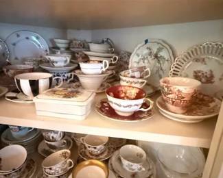 Vintage assorted floral porcelain teacups and saucers cabinet lot
Condition: Good
Assorted porcelain and likely bone-china teacups, saucers, and small plates/cups displayed in a cabinet. Visible motifs include floral sprays, gold trim, and some more decorative tea-party style pieces. The grouping appears to be a mixed lot rather than one uniform set.