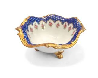 Scalloped blue-and-gold porcelain footed bowl with pink rose decoration
Condition: Good
Single small decorative porcelain footed bowl with four or more feet, scalloped rim, cobalt-blue border with gold detailing, and pink rose sprigs inside. Likely used as a decorative serving or display piece rather than everyday tableware.