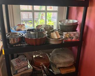 Assorted stainless steel and nonstick cookware and bakeware lot
Condition: Good
Assorted used kitchenware lot on shelving: several stainless-steel pots and bowls, a few nonstick or dark-coated pans, covered dishes, glass baking pieces, and miscellaneous bakeware/serving items. Secondary objects on the shelf are only included insofar as they appear to be part of the same kitchen lot.