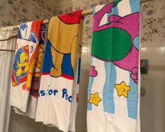 Vintage cartoon character beach towel lot of 3
Condition: Good
Assorted vintage-style children’s cartoon bath/beach towels in bright colors. Visible designs include a Tweety-like character on the left, a yellow bear-like character in the center, and a purple/green character motif on the right. Condition appears used/displayed; no tears or stains are clearly visible in the photo, but edges and reverse sides are not shown.
