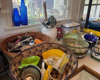 Mixed vintage kitchenware countertop lot with wicker baskets, blue glass bottles, bowls, and canisters
Condition: Good
Assorted countertop lot containing at least two wicker baskets, several glass bottles/jars, clear drinking glasses, a basket-weave style canister or dish, bowls, utensils, and small miscellaneous kitchen/serving items. Appears to be a grab-bag estate lot with mixed completeness and mixed eras rather than a single coordinated set.
