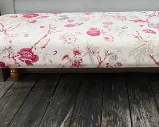 vintagestyle pink floral upholstered ottoman bench with turned wooden legs.