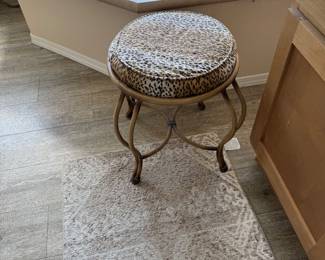 Vintage Leopard Print Vanity Stool — Charming and stylish round vanity stool featuring a beautifully curved metal base with graceful, decorative legs. The generously padded circular seat is upholstered in an eye-catching leopard-style fabric, making it a wonderful accent piece for a bathroom vanity, dressing area, bedroom, or makeup table. A unique combination of vintage elegance and bold style.