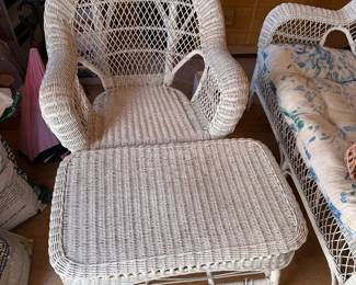 Vintage White Wicker Armchair with Matching Ottoman — Beautiful and inviting wicker lounge chair featuring a high rounded back, graceful curved arms, and classic woven construction. Includes the matching large wicker ottoman/footstool, creating a comfortable and stylish seating set. Perfect for a sunroom, covered porch, bedroom, cottage, or coastal-inspired décor. The white finish gives this charming vintage set a timeless look.