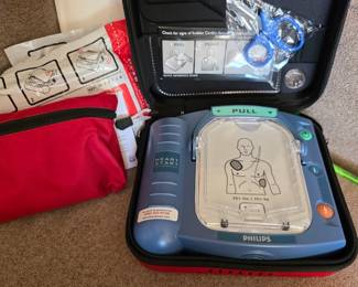 Philips HeartStart AED / automated external defibrillator with carrying case, manuals and accessories. Older unit; electrode pads shown are expired and unit has not been certified or tested for current emergency use. Sold as-is for replacement parts, training, collection or refurbishment as appropriate.