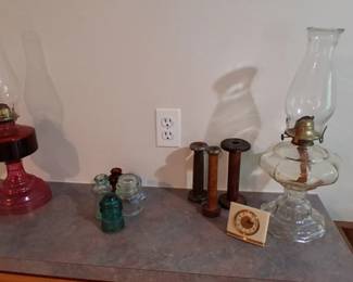 two kerosene oil lamps, glass insulators, wooden spools, and a small clock