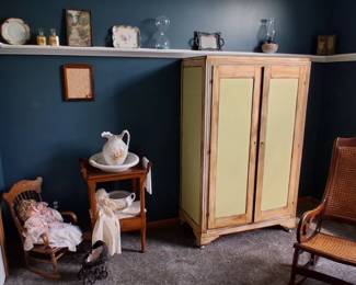 antique-style armoire with pale green panels, a washstand with a pitcher and bowl, and two rocking chairs