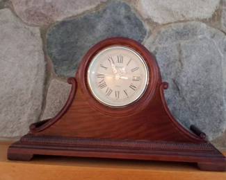 traditional wooden humpback or tambour-style mantel clock with a mahogany or cherry finish