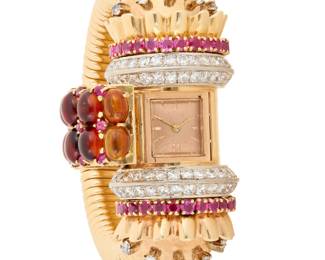 301 A Retro 14K Gold and Citrine Surprise Watch Featuring a tubogas bracelet centering a bow style motif set with oval cabochon citrine, round rubies and transition-cut diamonds hiding a rose gold dial with baton hour markers, c. 1940's Length: 7 1/2 in., Wisth: 1 in. 95.6 grams gross Estimate: $12,000 - $18,000
