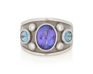 42 An 14K White Gold, Tanzanite and Diamond Ring Centering an oval tanzanite weighing approximately 3.10 carats, flanked by two round blue topaz and ten round diamonds, signed CGJ Size: 8 13.9 grams gross This lot is offered at no reserve. Estimate: $1,000 - $1,500