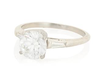 119 A Platinum and Diamond Ring Centering a round brilliant-cut diamond weighing 1.46 carats, flanked by two tapered baguettes Size: 6 1/2 4.5 grams gross Accompanied by a GIA Report numbered #5241029231, dated August 6, 2026, stating the diamond as Natural with a color grade of D and a clarity grade of VVS2, no fluorescence. Estimate: $3,000 - $5,000