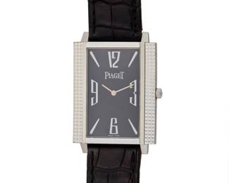 306 Piaget: An 18K White Gold 'Black Tie' Watch Dial: 17.8 mm, rectangular black dial with Panerai hour markers Case: 28.00 mm Case number: 90300, 880846 Closure: black strap with and 18k white gold buckle clasp Signed: dial, case, strap and clasp, with signed box Inner circumference: 7 - 8 1/4 in. 54.1 grams gross Estimate: $5,000 - $7,000