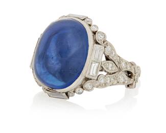 125 An Art Deco Platinum, Sapphire and Diamond Ring Centering an oval double cabochon weighing approximately 36.80 carats, set in an ornate mount featuring single-cut and baguette diamonds weighing approximately 2.06 carats, finished with a diamond link shank Size: 6 1/2 16.7 grams gross Accompanied by a AGL Report numbered #1158850, dated August 25, 2026, stating the Sapphire as natural Corundum of Sri Lankan origin with No heat enhancements. Estimate: $25,000 - $35,000