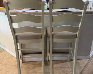 COASTAL UPHOLSTERED BAR-HEIGHT STOOLS — PAIR: Soft Cream Finish • Neutral Upholstered Seats • Sculpted Ladder Backs • Turned-Leg Detailing • Metal Footrest Protectors • Casual Coastal / Transitional Style