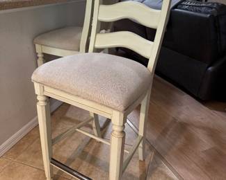 COASTAL UPHOLSTERED BAR-HEIGHT STOOLS — PAIR: Soft Cream Finish • Neutral Upholstered Seats • Sculpted Ladder Backs • Turned-Leg Detailing • Metal Footrest Protectors • Casual Coastal / Transitional Style