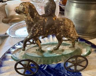 Antique metal pull toy featuring a dog with a small rider mounted on its back, wheeled platform