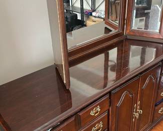 dark wood triple dresser and tri-fold beveled mirror