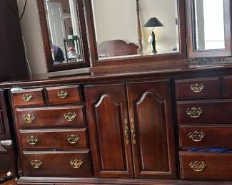 dark wood triple dresser and tri-fold beveled mirror