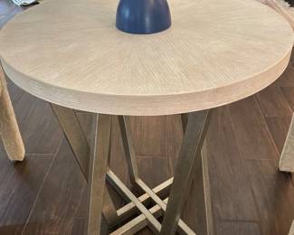 Light textured round, top resting on interlocking angular, metal legs