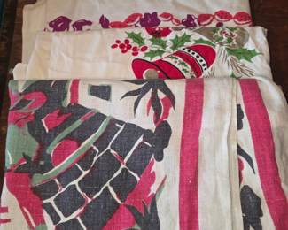  The image shows a stack of folded vintage fabric items that appear to be retro printed tablecloths or kitchen linens.
