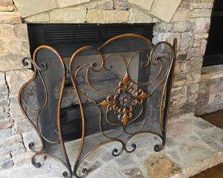 Ornate scrolled iron fireplace screen with medallion